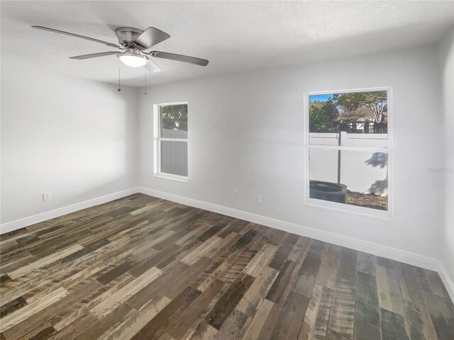 unfurnished room with plenty of natural light, baseboards, and dark wood-style flooring