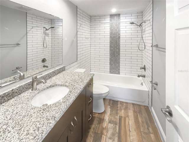 bathroom with baseboards, toilet, wood finished floors, tub / shower combination, and vanity