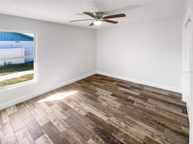 empty room with dark wood-style floors, ceiling fan, and baseboards