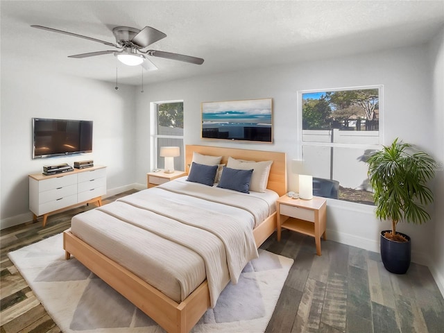 bedroom with multiple windows, baseboards, and wood finished floors