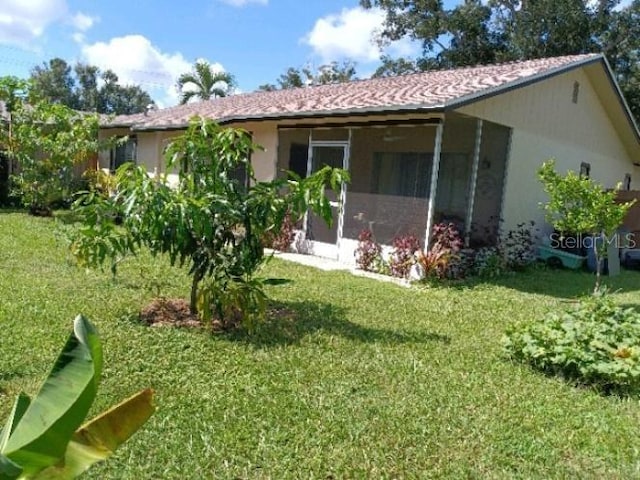 back of house with a yard, a sunroom, and stucco siding