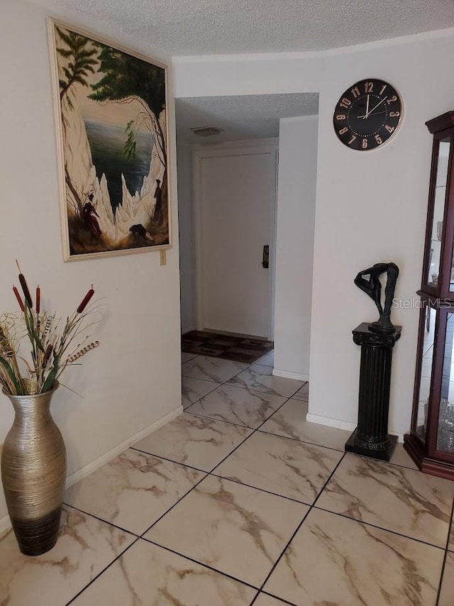 corridor with marble finish floor, visible vents, baseboards, and a textured ceiling