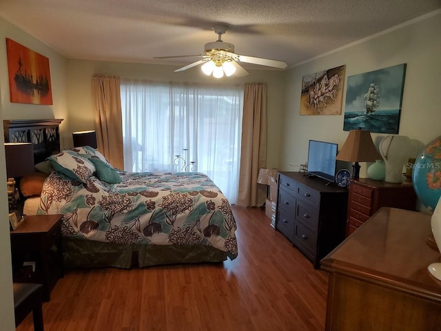 bedroom featuring a textured ceiling, ornamental molding, wood finished floors, and a ceiling fan