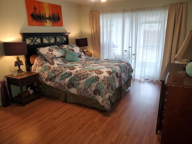 bedroom with multiple windows and wood finished floors