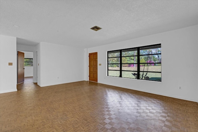 empty room featuring baseboards, visible vents, and a textured ceiling