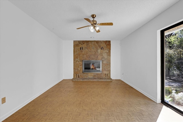 unfurnished living room featuring a fireplace, a textured ceiling, baseboards, and ceiling fan