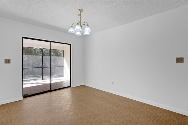 unfurnished room featuring a chandelier, a textured ceiling, and baseboards