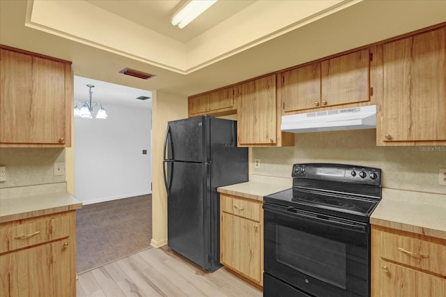 kitchen featuring under cabinet range hood, visible vents, light countertops, light wood-type flooring, and black appliances