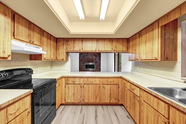 kitchen with light wood finished floors, a raised ceiling, light countertops, black electric range oven, and under cabinet range hood