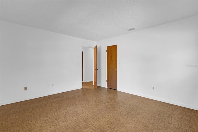 spare room featuring visible vents, a textured ceiling, and baseboards