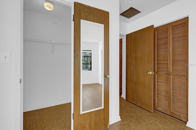 unfurnished bedroom with a textured ceiling, a closet, visible vents, and baseboards