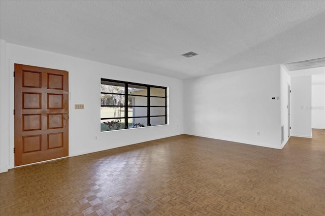 spare room with a textured ceiling, visible vents, and baseboards