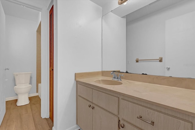 full bath with toilet, baseboards, wood finished floors, and vanity