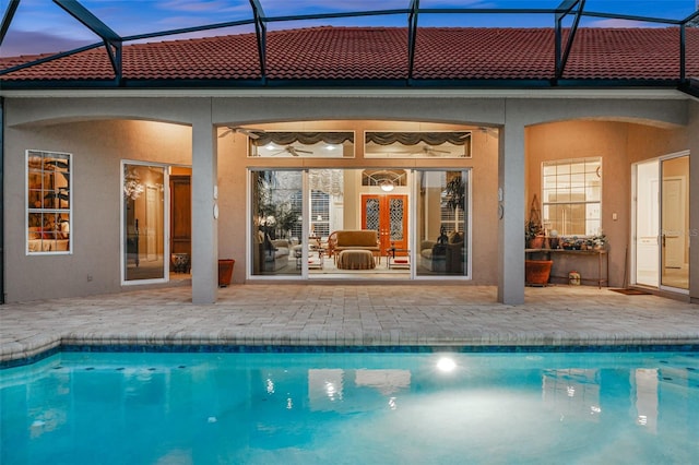 back of house at dusk with an outdoor pool, a patio, and stucco siding