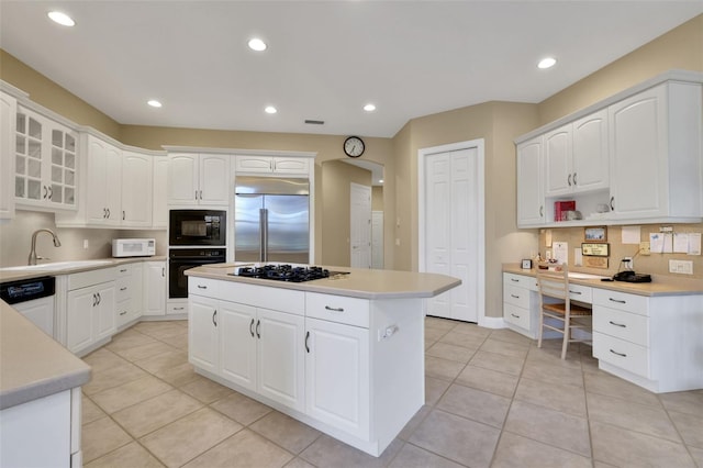 kitchen featuring white cabinets, a kitchen island, glass insert cabinets, black appliances, and a sink