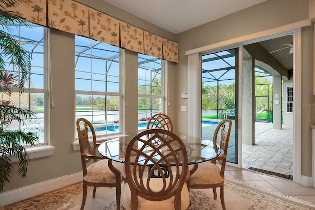 dining space featuring light tile patterned floors, a sunroom, and baseboards