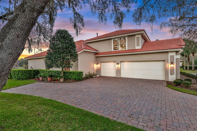 mediterranean / spanish house with decorative driveway, a tile roof, and stucco siding