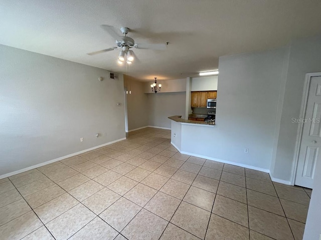 unfurnished living room with light tile patterned floors, visible vents, baseboards, and ceiling fan with notable chandelier