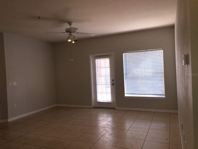 unfurnished room with light tile patterned floors, baseboards, and ceiling fan