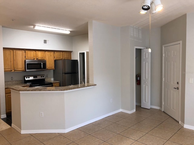 kitchen with light tile patterned floors, baseboards, visible vents, a peninsula, and stainless steel appliances