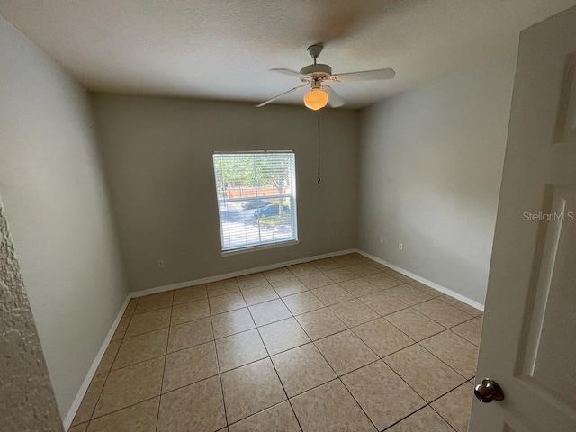 spare room featuring light tile patterned floors, baseboards, a textured ceiling, and ceiling fan