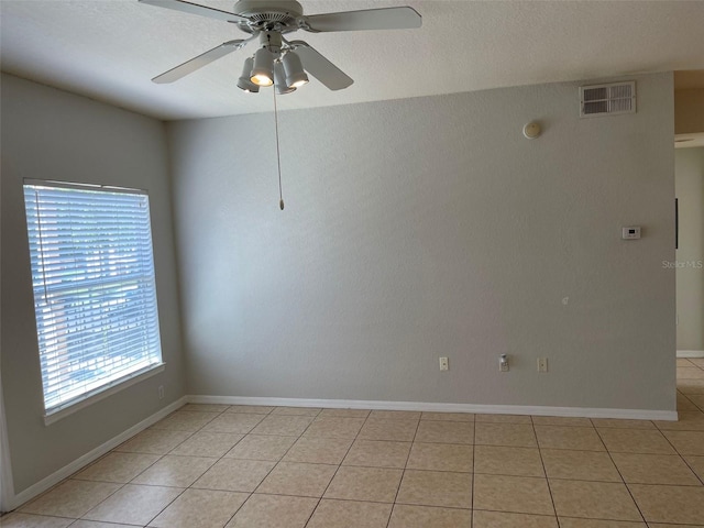 empty room featuring light tile patterned flooring, a ceiling fan, visible vents, and baseboards