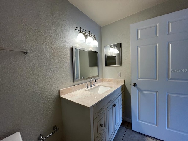 half bath with tile patterned floors, vanity, and a textured wall