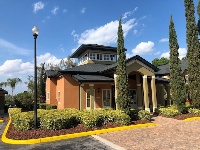 view of front facade featuring stucco siding and a shingled roof