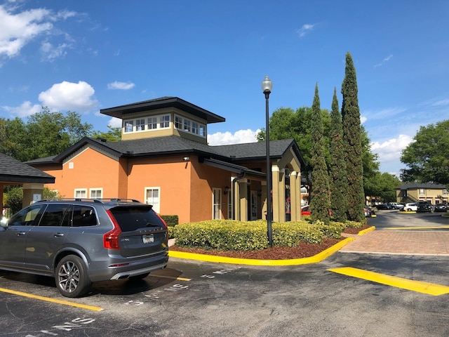 exterior space with stucco siding and uncovered parking