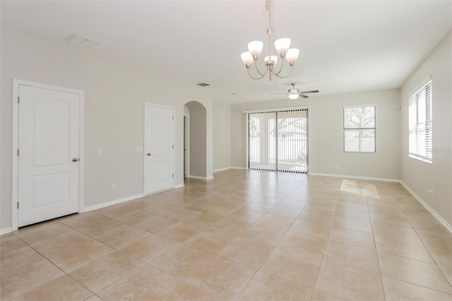 empty room featuring light tile patterned floors, plenty of natural light, arched walkways, and baseboards