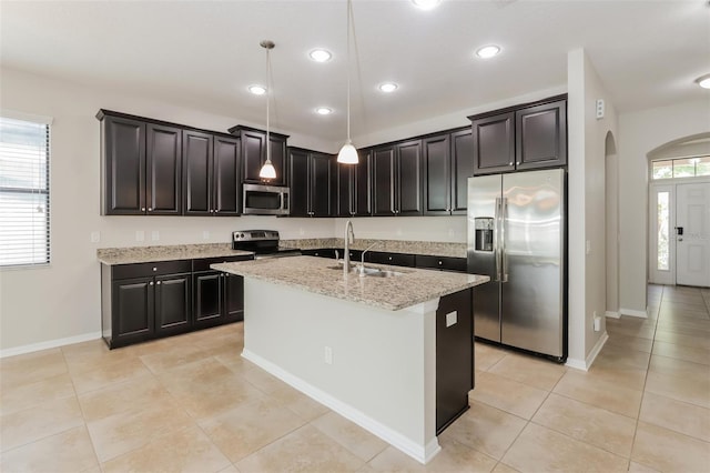 kitchen with arched walkways, light stone counters, stainless steel appliances, a sink, and pendant lighting