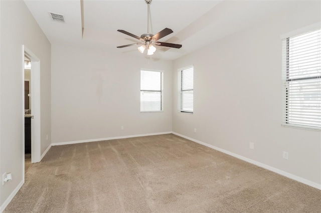 empty room with baseboards, visible vents, ceiling fan, and light colored carpet