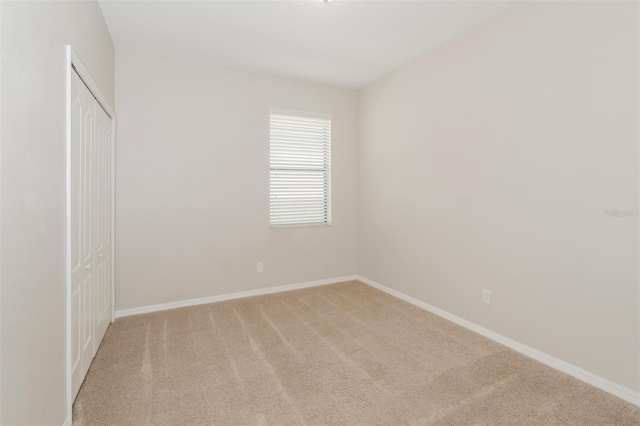 empty room featuring light carpet and baseboards