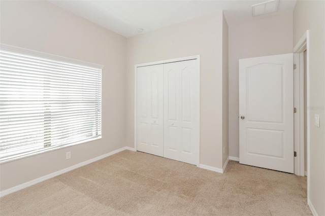 unfurnished bedroom featuring carpet floors, visible vents, baseboards, and a closet