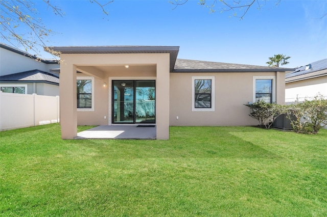 rear view of property featuring a patio, a lawn, fence, and stucco siding