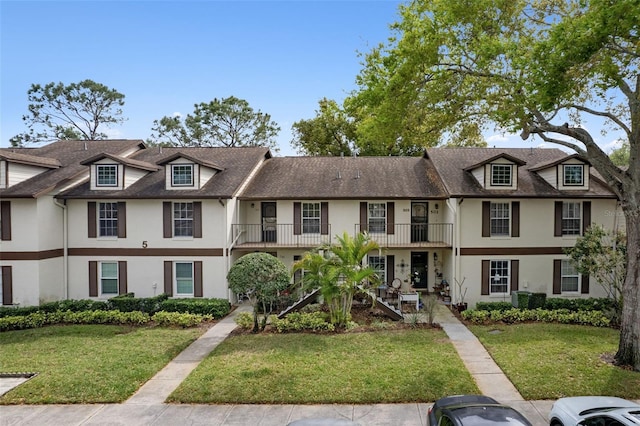 view of property with stucco siding, a balcony, and a front yard