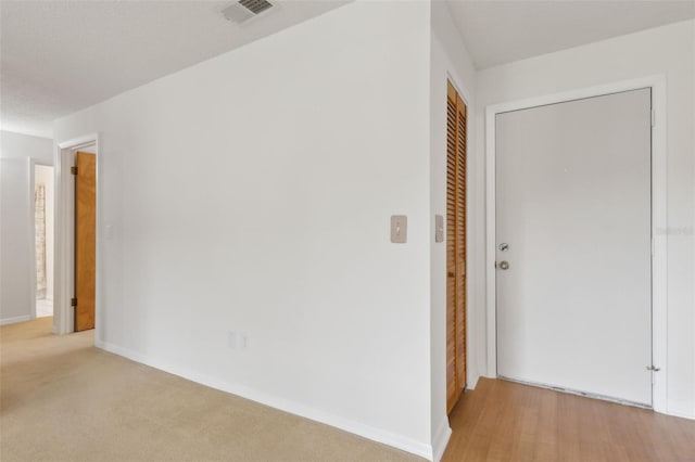 hall featuring visible vents, baseboards, and light carpet