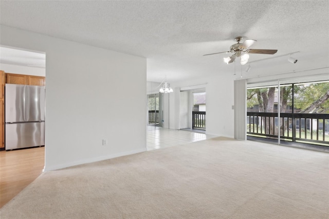 unfurnished living room with baseboards, light carpet, a textured ceiling, and ceiling fan with notable chandelier