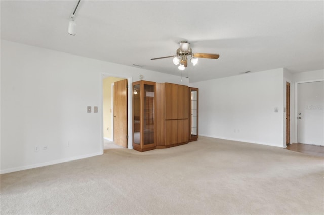 empty room with visible vents, baseboards, ceiling fan, light carpet, and rail lighting