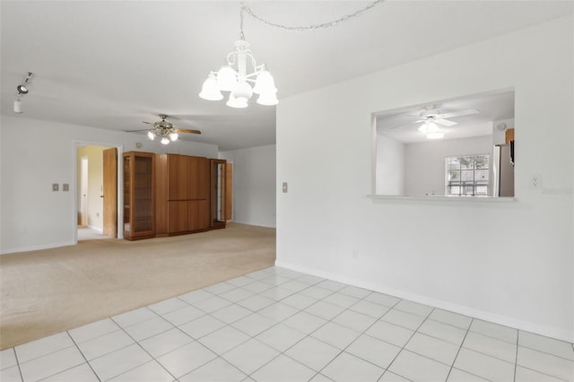 unfurnished room featuring light carpet, ceiling fan with notable chandelier, baseboards, and light tile patterned flooring