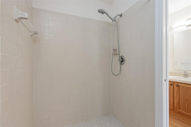 full bathroom featuring a tile shower and vanity