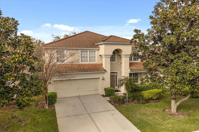 mediterranean / spanish-style house with driveway, a tile roof, a garage, and stucco siding