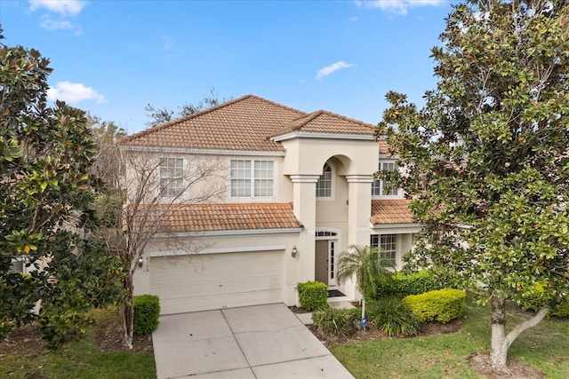 mediterranean / spanish-style home with a tile roof, an attached garage, driveway, and stucco siding