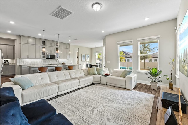 living area featuring baseboards, dark wood finished floors, visible vents, and recessed lighting