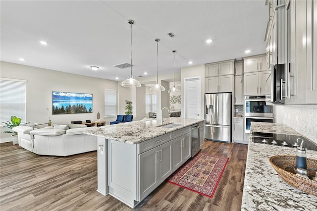 kitchen with dark wood finished floors, gray cabinets, visible vents, appliances with stainless steel finishes, and a sink