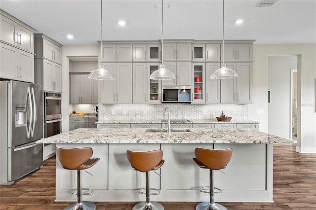 kitchen with appliances with stainless steel finishes, gray cabinets, dark wood-type flooring, and backsplash