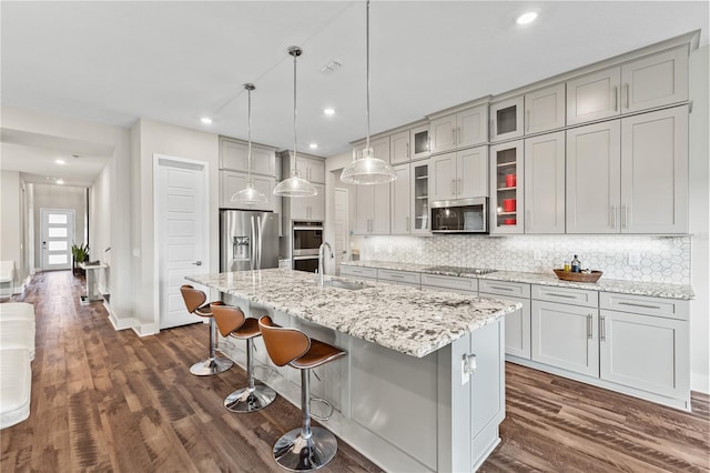 kitchen featuring appliances with stainless steel finishes, dark wood-style flooring, a sink, and tasteful backsplash