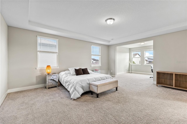 carpeted bedroom with a textured ceiling, multiple windows, and baseboards