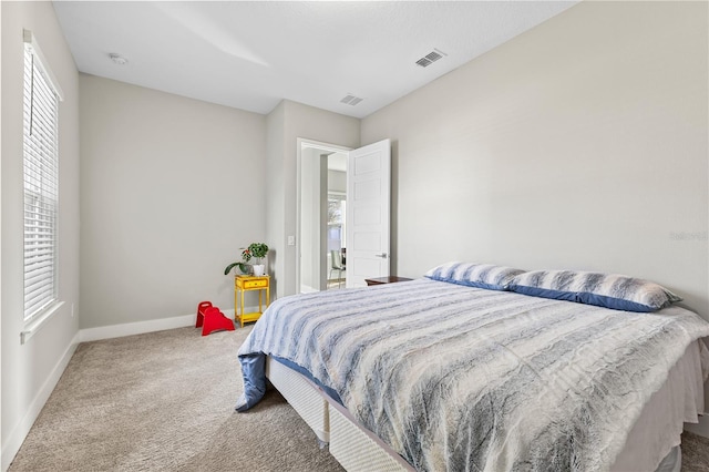 bedroom featuring visible vents, multiple windows, baseboards, and carpet flooring