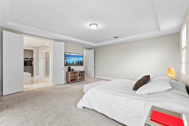 bedroom with carpet floors, a tray ceiling, and visible vents